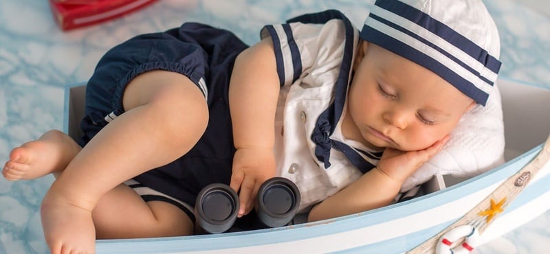 un bébé en costume de marin dort dans un bateau