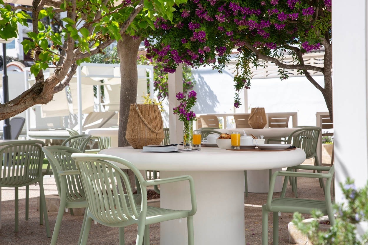 Table extérieure dressée avec petit-déjeuner sous les bougainvilliers à Casual Bahía Ibiza.