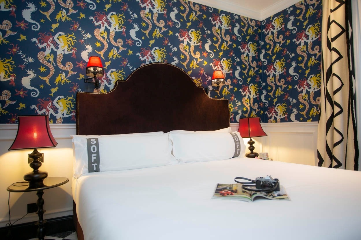 Luxuriöses Bett im Casual Eclettico Milano Hotel, Mailand, mit fantasievoller Tapete und roten Lampen.