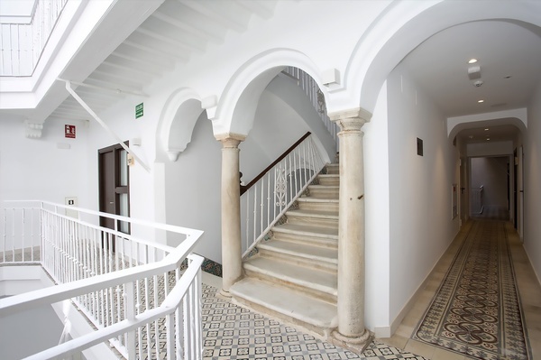 a hallway with stairs and a green exit sign