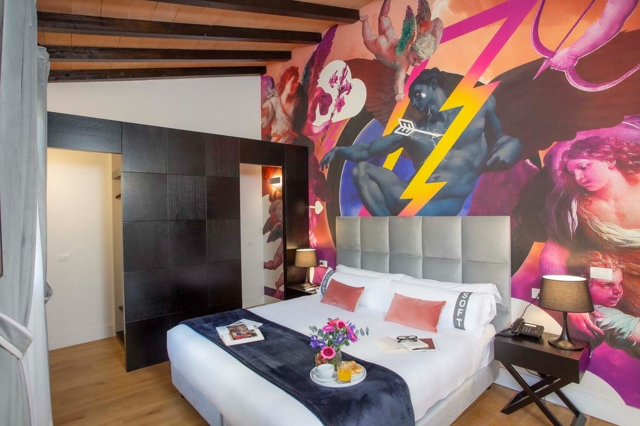 Komfortables Zimmer im Casual Rinascimento Firenze: Wandmalerei, Kingsize-Bett, moderner Kleiderschrank. Zentrales Hotel mit Pool in Florenz.