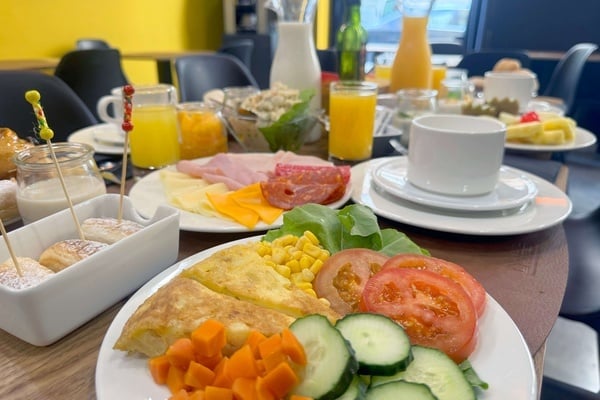 a table topped with plates of food and drinks including orange juice