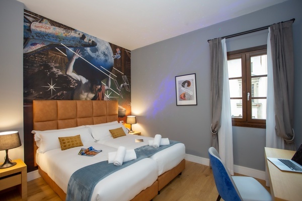 a bedroom with two beds and a mural on the wall that says nasa