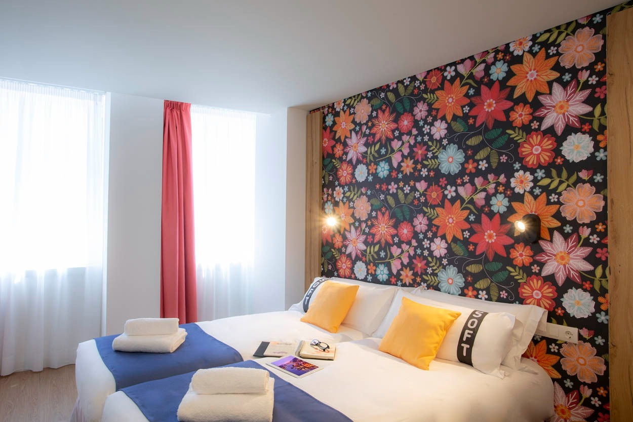 Camere Casual Raízes Porto con carta da parati floreale e letti gemelli accoglienti.