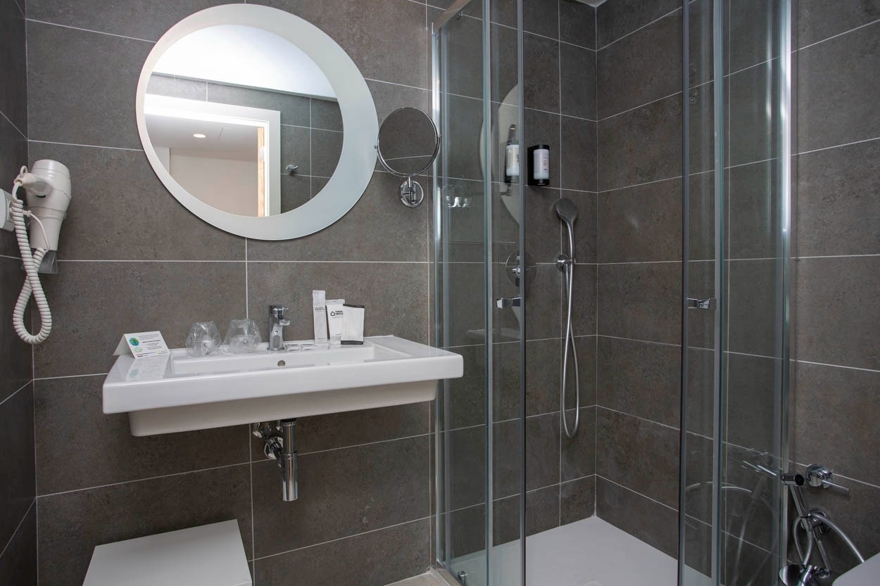 Bagno moderno con doccia e lavabo, parte di Casual Raízes Porto - Boutique hotel vicino a Santa Catarina.