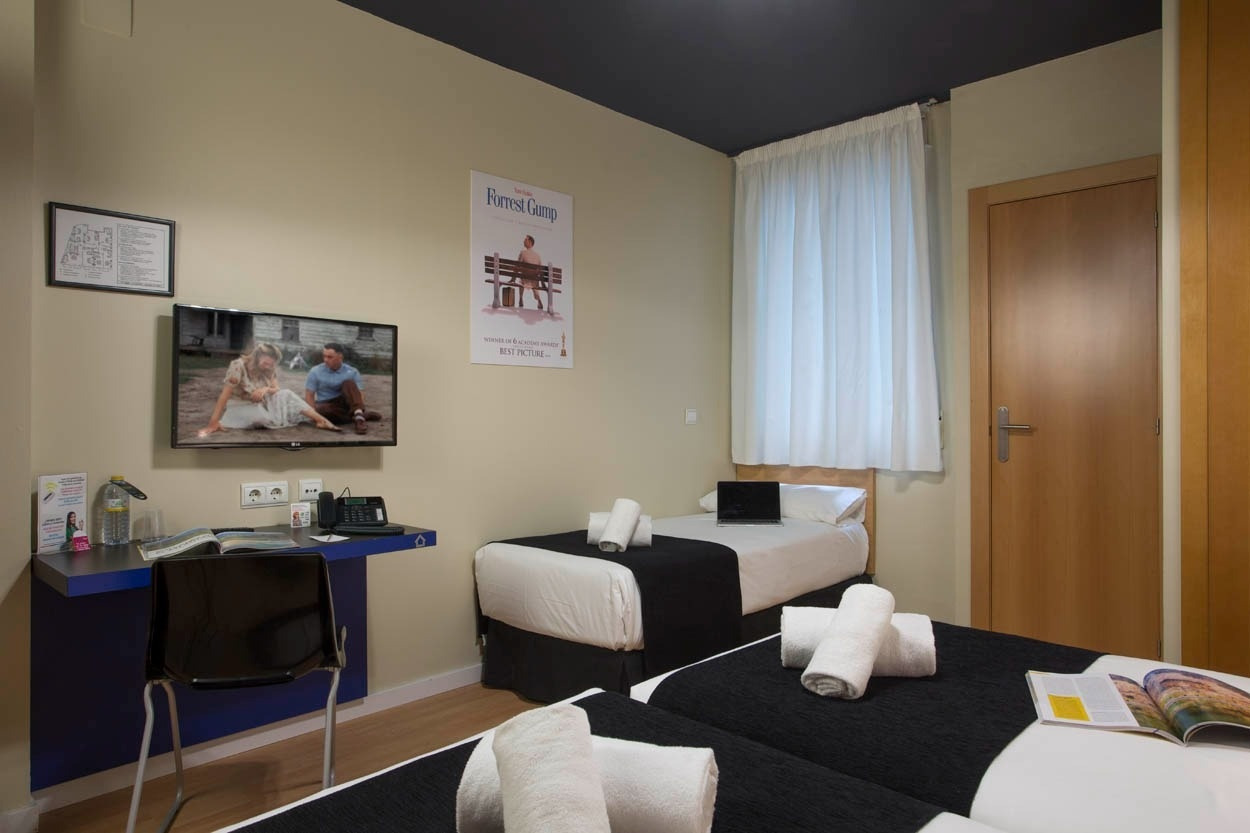 Zimmer im Casual del Cine Valencia: Betten, Schreibtisch, TV, Poster & Vorhänge.