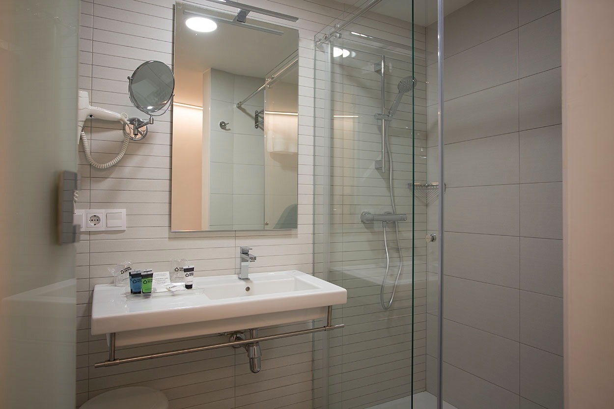Modernes Badezimmer mit Dusche, Waschbecken und Spiegel im Casual de las Olas San Sebastián.