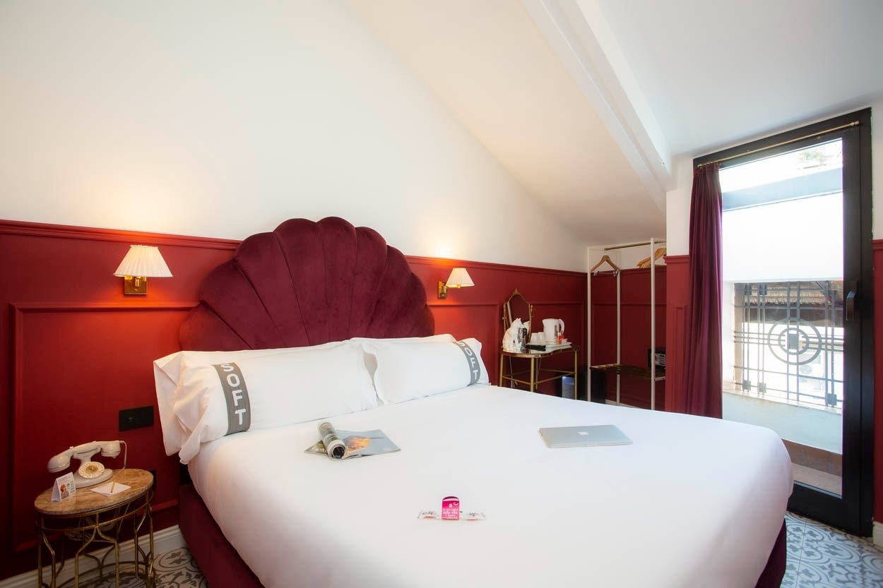 Ein luxuriöses Bett mit rotem Kopfteil und ein Balkon im Casual Eclettico Milano – Hotel Mailand nähe Bahnhof Centrale.