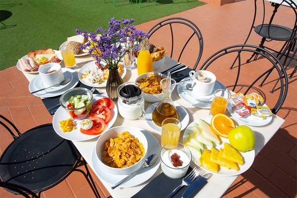 una mesa llena de comida y bebidas con un jarrón de flores moradas