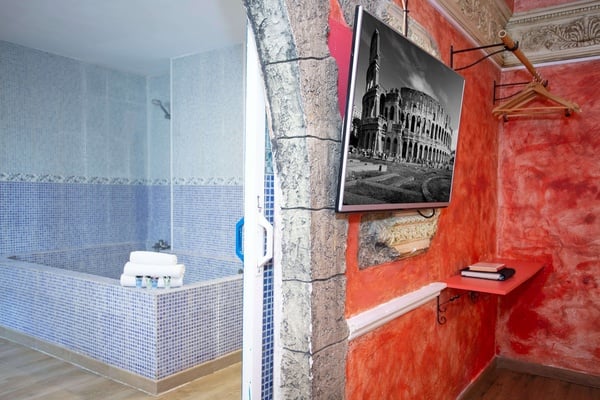 un baño con una bañera y una televisión en la pared