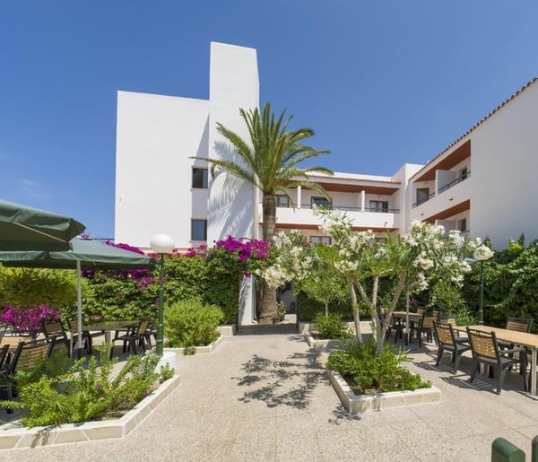 un grand bâtiment blanc avec des tables et des parasols à l' extérieur