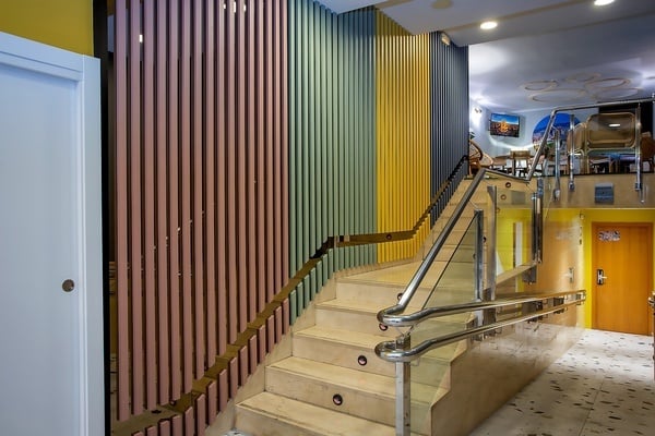 un escalier avec un rail en verre et un mur coloré
