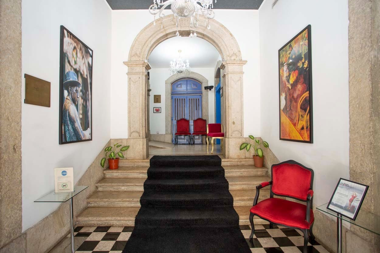 Elegante Lobby mit Stuck-Arch, Kunst und rotem Sessel im Casual Belle Époque - Boutique-Hotel in Lissabon.