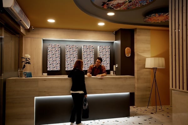 une femme parle à un homme au comptoir de réception d' un hôtel