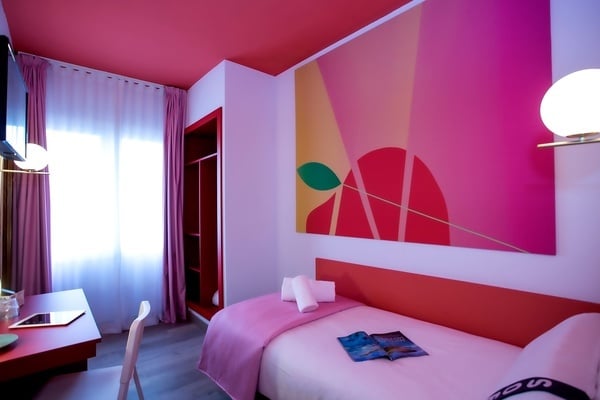 une chambre avec un lit , une table et une peinture sur le mur