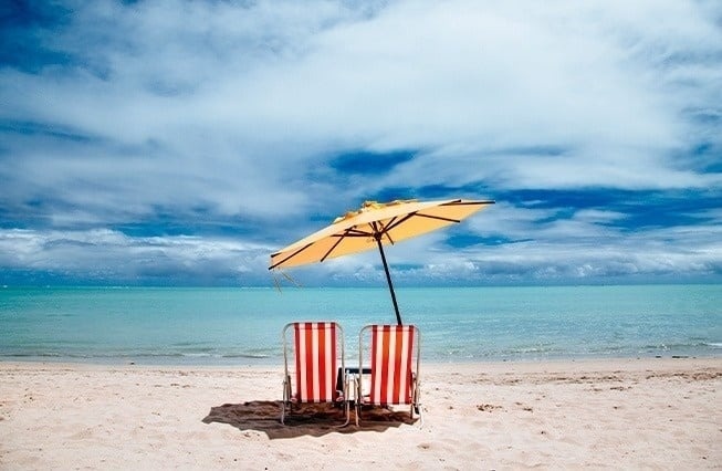 dos sillas de playa y un paraguas en la playa