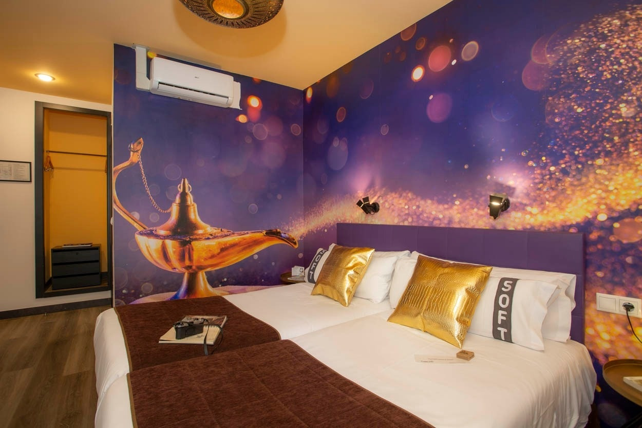 Zwei Betten im Casual del Cine Valencia – Themenhotel mit Aladdin-Wandbild und goldenen Kissen.
