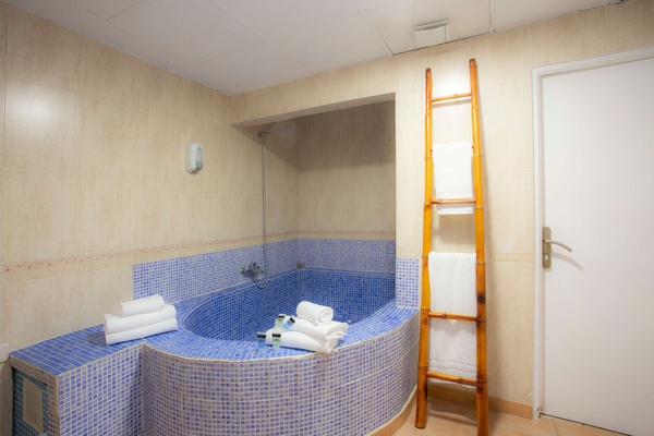 un baño con una bañera y una escalera de bambú