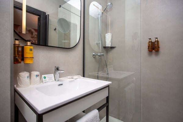 a bathroom with a sink and two bottles of rituals on the wall