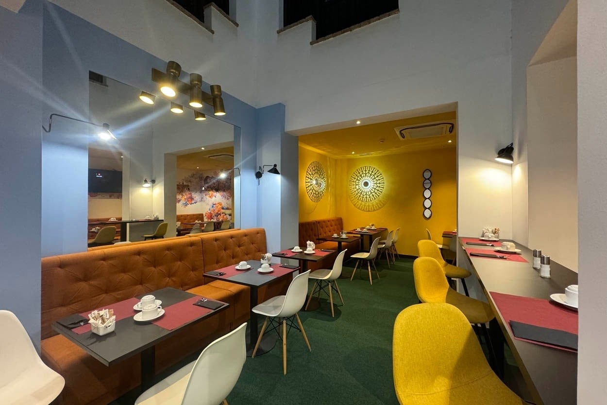 Casual Ilbira Granada: Comedor moderno con asientos tipo sofá y mesas minimalistas.