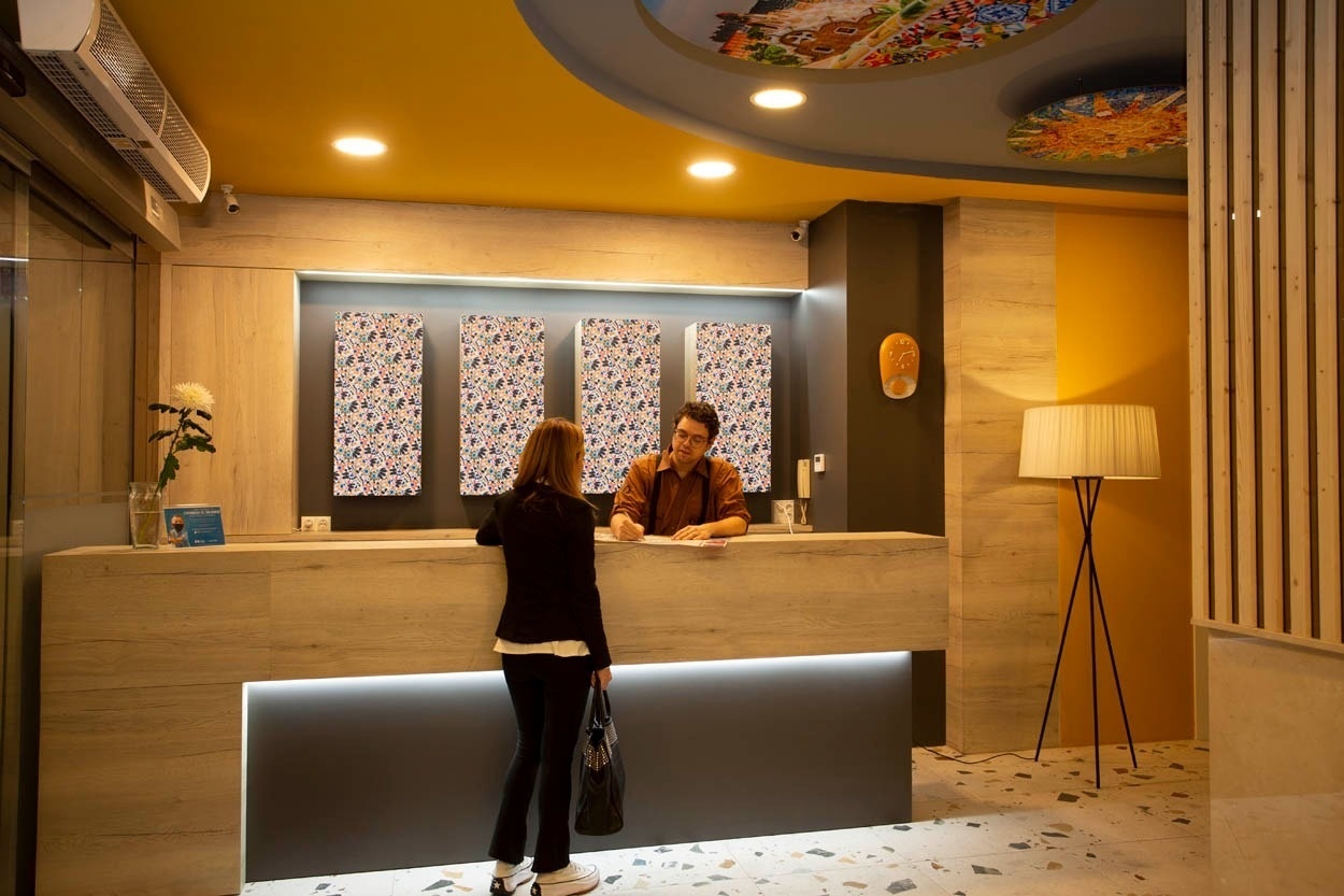 Receptie van Casual Colours Barcelona - Hotel, met gast en receptionist.