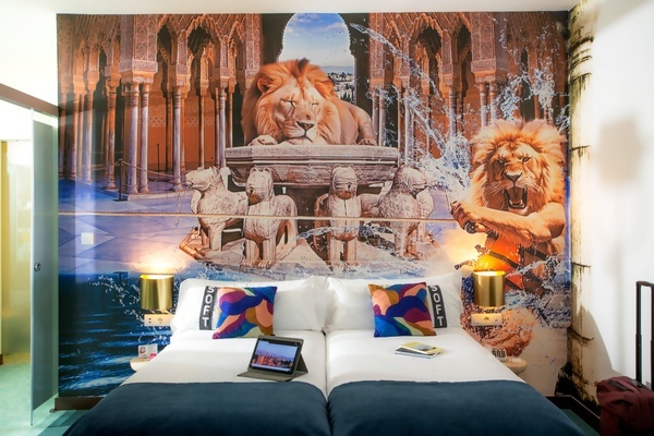um quarto de hotel com duas camas e uma pintura de leões na parede