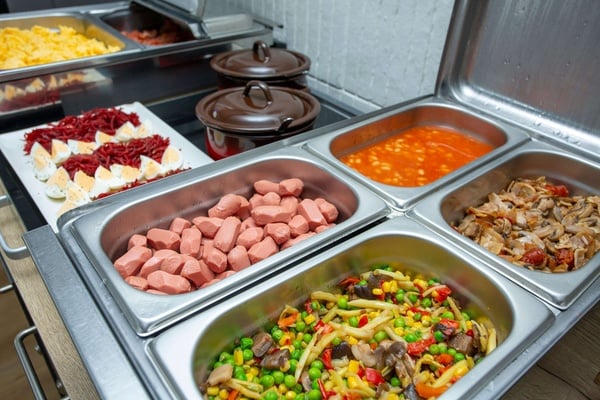 a buffet filled with a variety of food including sausages and vegetables