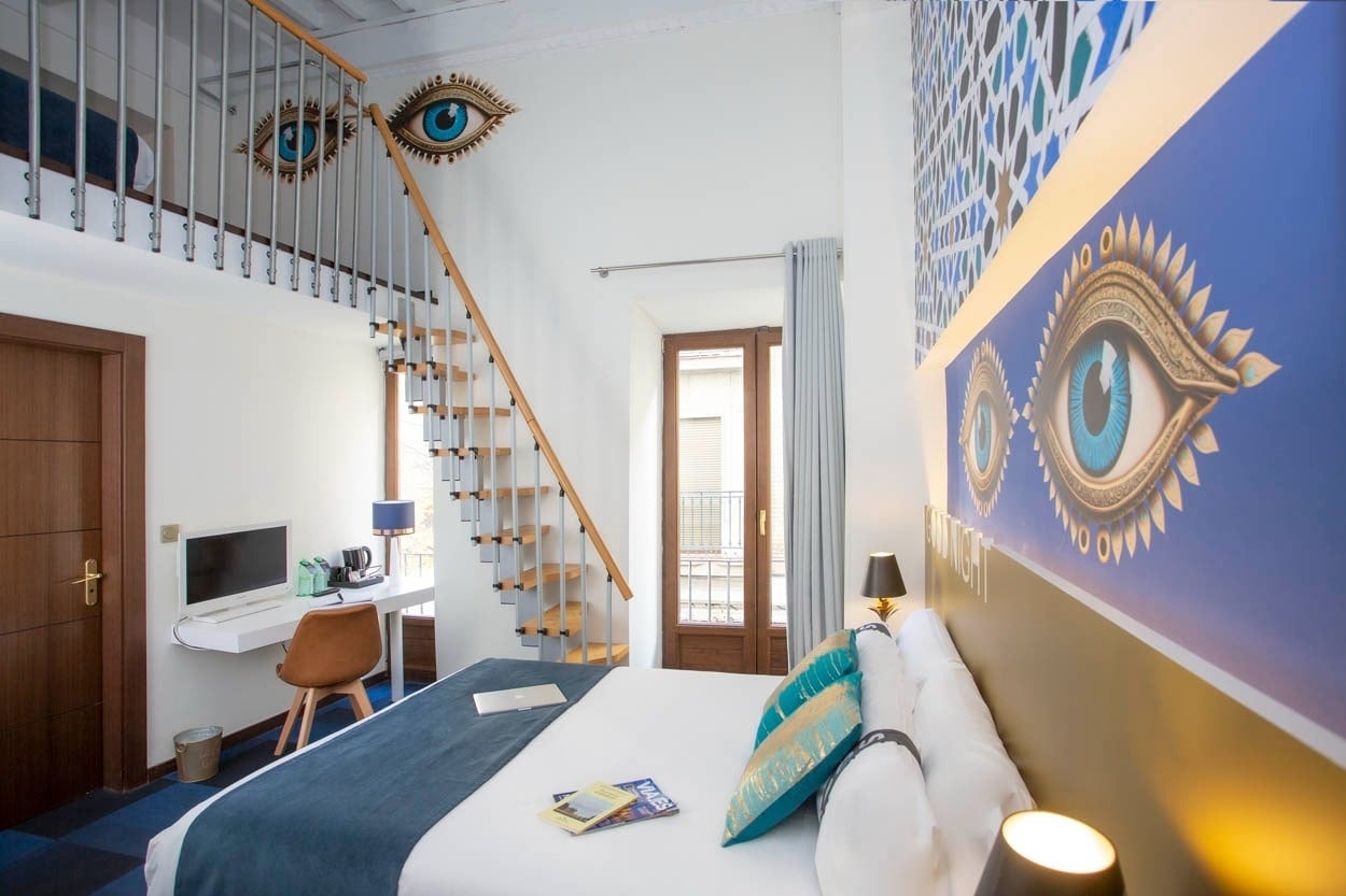 Casual Ilbira Granada: dormitorio con estilo, escalera y arte de ojos en el centro histórico.