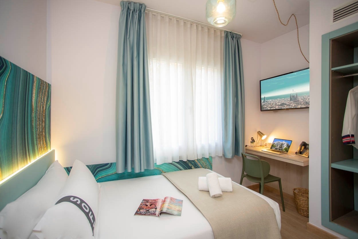 Moderne hotelkamer in Casual Colours Barcelona, met bureau, tv en comfortabel bed. Boek nu uw verblijf in Barcelona!