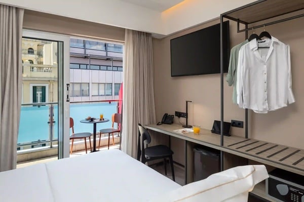 een hotelkamer met uitzicht op een zwembad en een tafel en stoelen