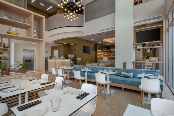 een restaurant met witte tafels en stoelen en een blauwe bank