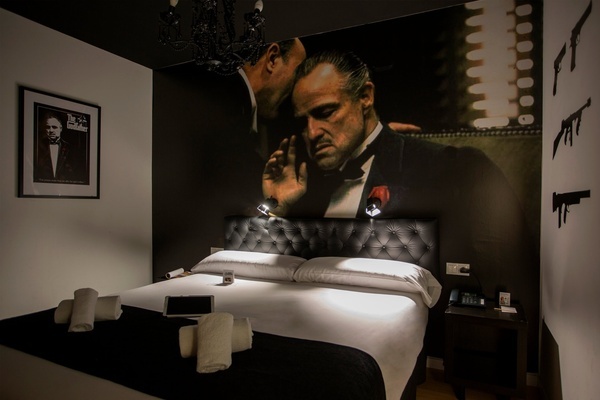 una habitación con una cama y un cartel de el padrino en la pared