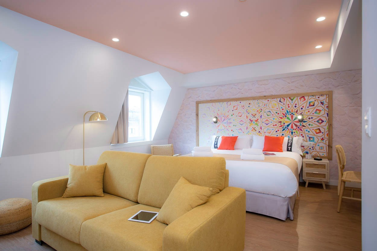 Camera da letto accogliente con divano giallo e letto king-size, Casual Raízes Porto.
