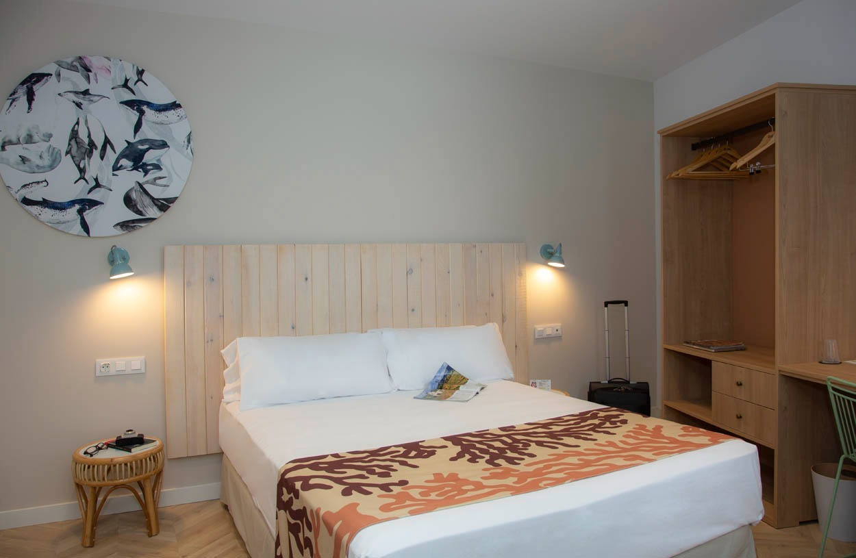 Schlafzimmer im Casual con Duende Cádiz: Gemütliches Doppelbett mit Wandkunst & Holzmöbeln, nahe dem Zentrum.