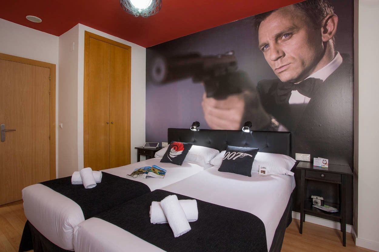 Themenzimmer im Casual del Cine Valencia: Doppelbett mit James Bond-Motiv, ideal für Filmfans.