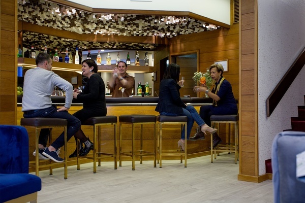 a group of people are sitting at a bar drinking