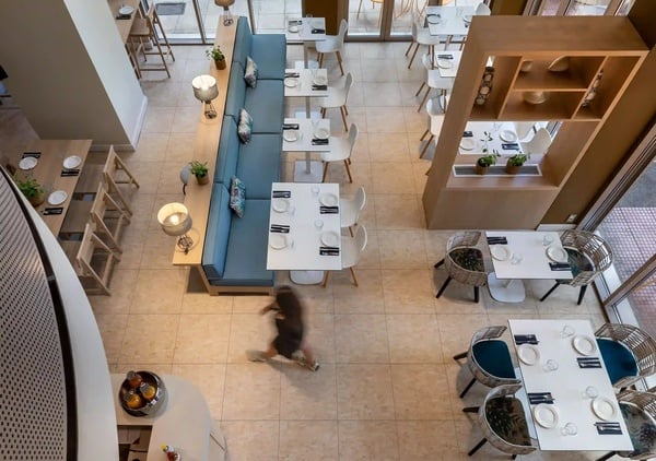 een vrouw loopt door een restaurant met tafels en stoelen