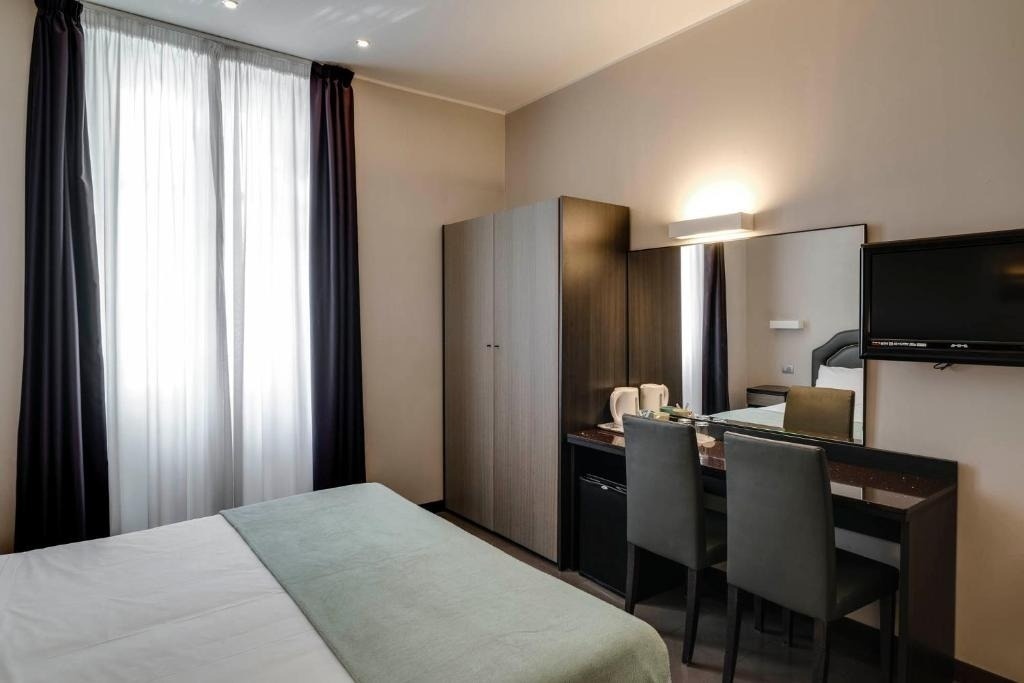 a hotel room with a bed a desk and a flat screen tv