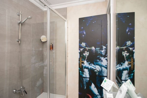 een badkamer met een douche en een spiegel met een schilderij aan de muur