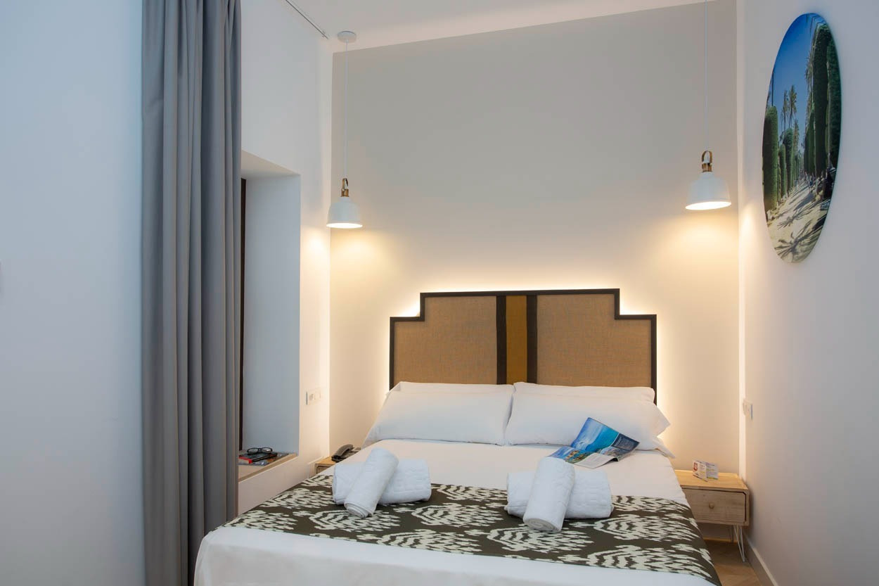 Gemütliches Doppelbett im Casual con Duende Cádiz Hotel mit stilvollem Kopfende & Stadtblick.