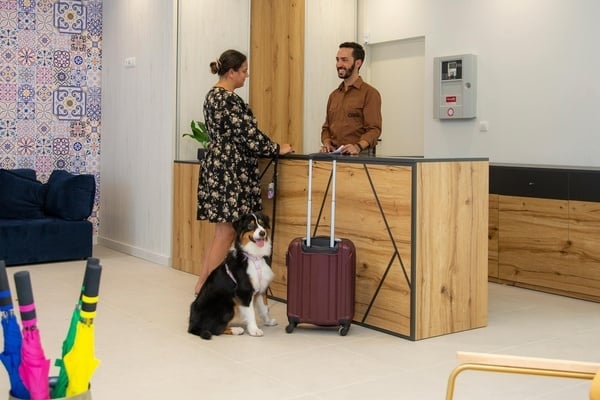 a man and a woman are standing at a counter with a dog standing next to them