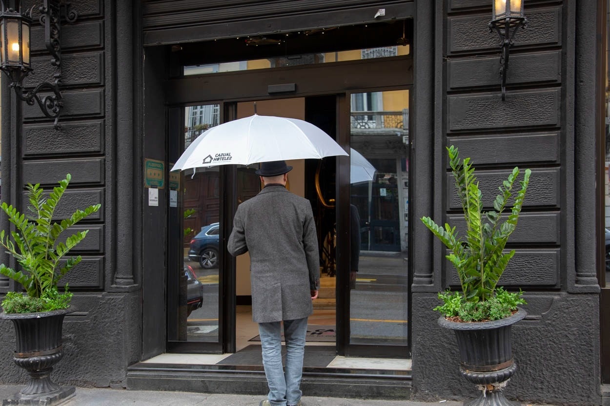 Mann mit Regenschirm betritt das Casual Eclettico Milano Hotel in Mailand.