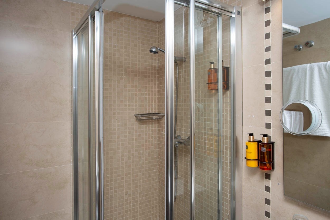 Ducha moderna con dispensadores de jabón en el baño del Casual Ilbira Granada.