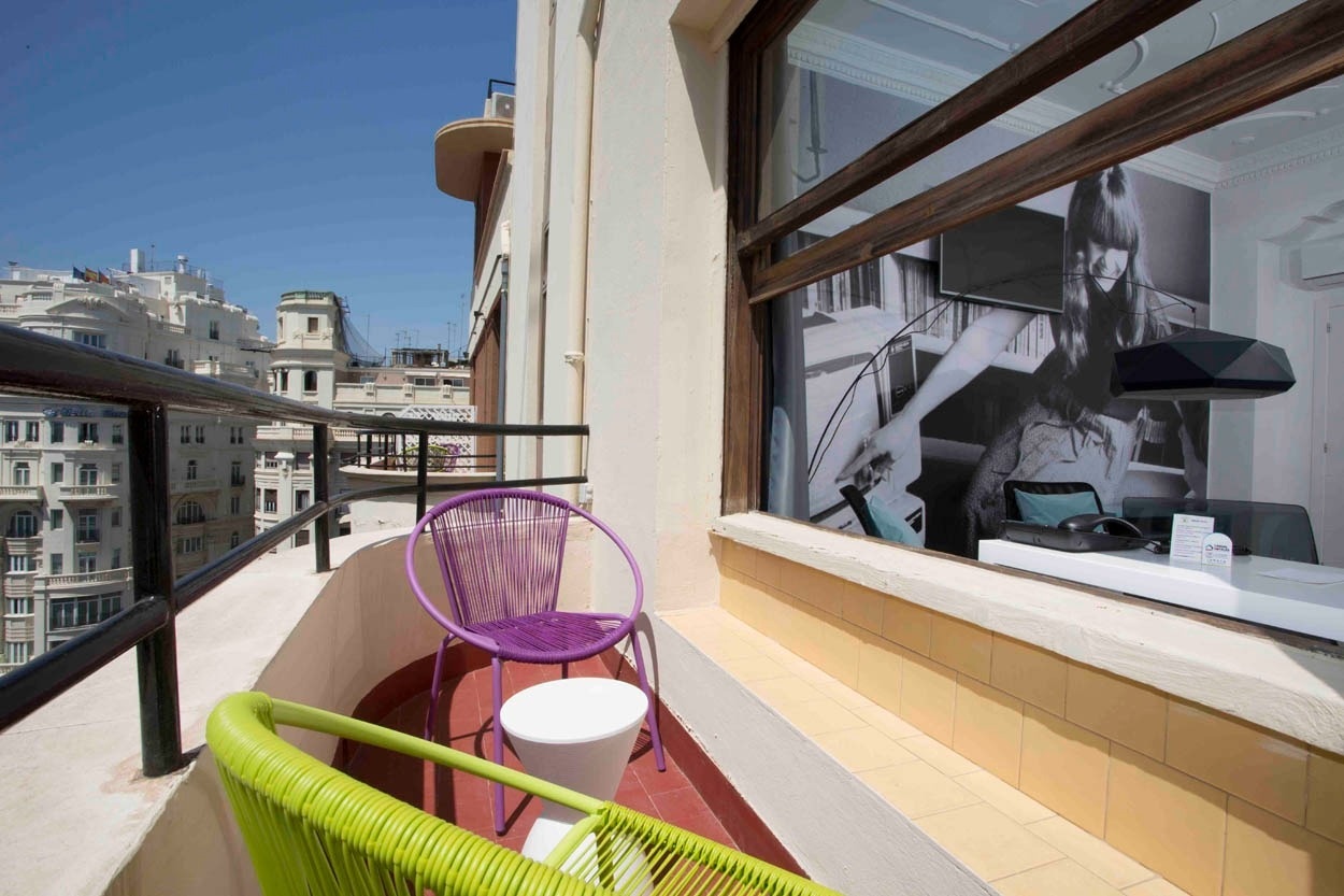 Balcón moderno con sillas de colores y vistas urbanas, perfecto para tu estancia en Casual Vintage Valencia.