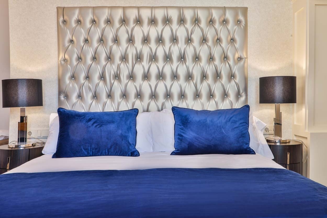 Komfortables Bett mit blauen Kissen und glamouröser Kopfstütze im Casual Belle Époque Hotel Lissabon.