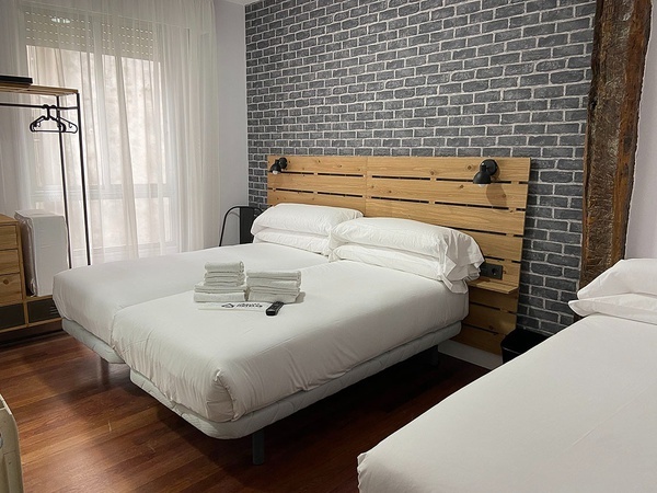 a hotel room with three beds and a brick wall