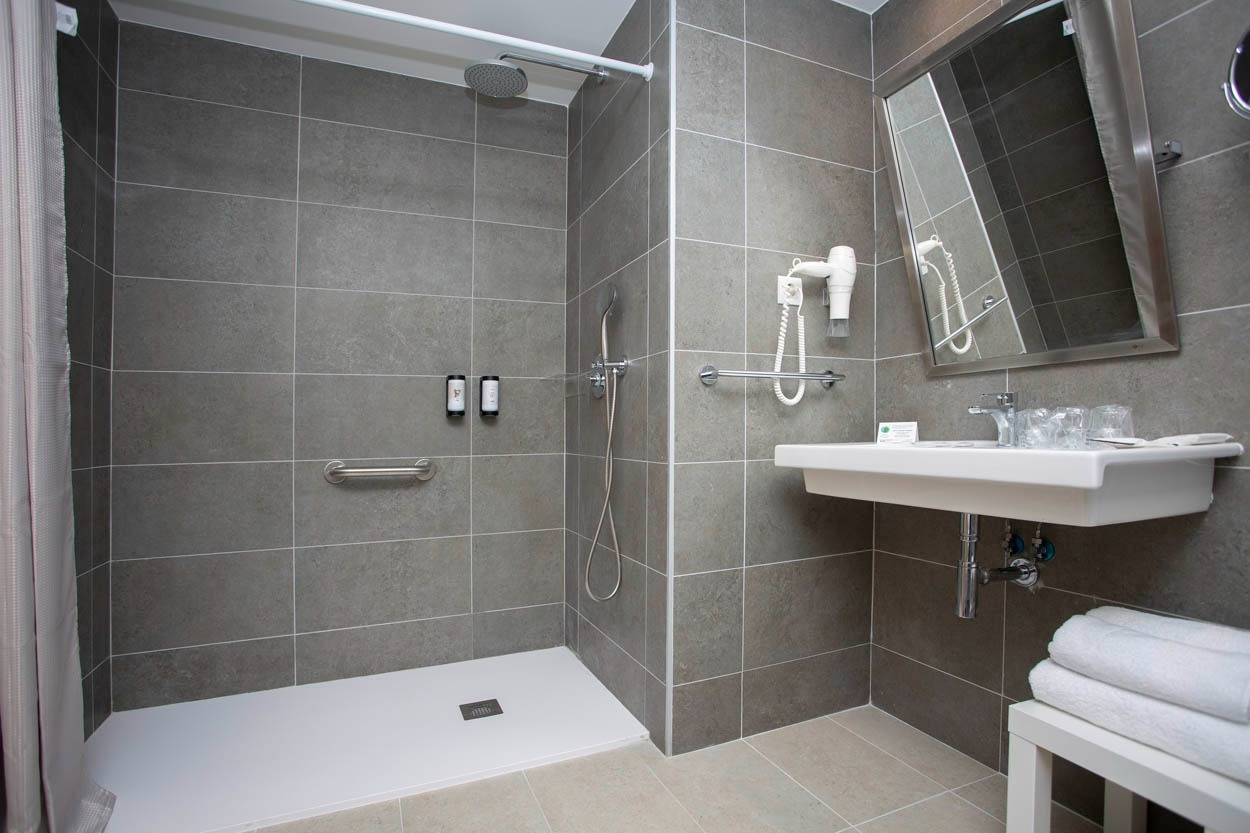 Bagno moderno di Casual Raízes Porto con doccia, lavandino e asciugacapelli.