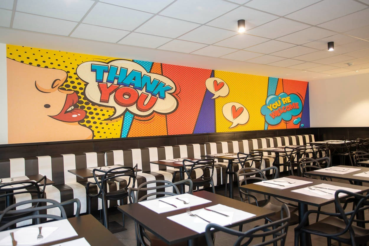 Casual Pop Art Benidorm: Farbenfrohe Pop-Art-Wandmalerei in einem Speisesaal mit gestreiften Sitzbänken und Tischen. Perfekt für Ihren legeren Aufenthalt in Benidorm.
