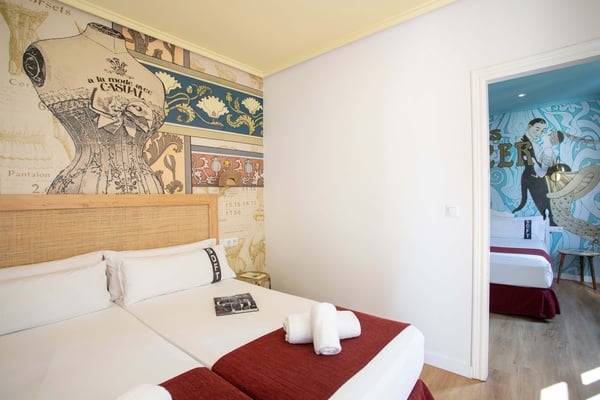 una habitación con dos camas y un mural en la pared que dice pantalones