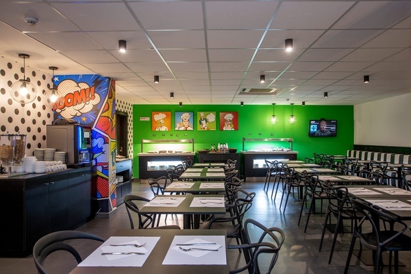 un restaurante con mesas y sillas y una nevera que dice boom